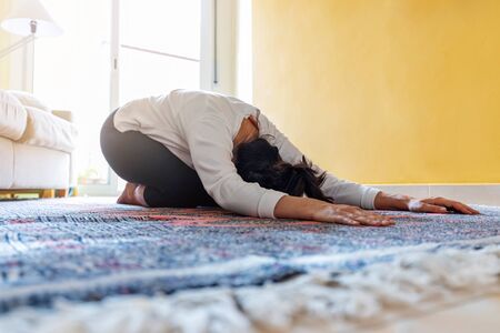 Pretty spanish girl doing yoga at home in the living room
