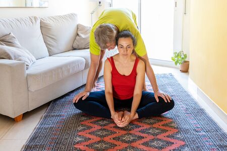 Middle aged couple practice stretching at home in sunlight