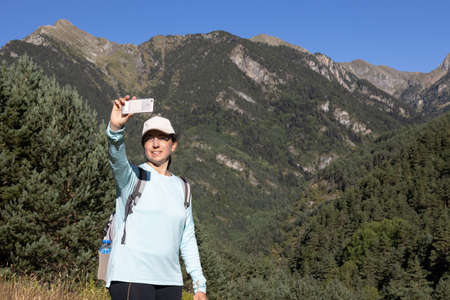 Young tourist woman take a picture from mountain with mobile phoneの写真素材