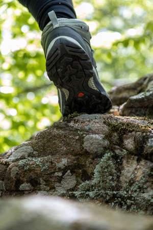 Boot of hiker on forest trail. Traveler feet are stepping on the rock. Adventure and hiking concept outdoor. Hipster lifestyleの写真素材