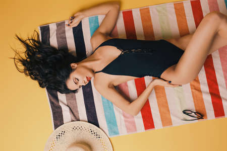 Beautiful and young lady in swimsuits on colorful towelの写真素材