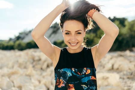 Young woman posing near the beautiful mountains dressed colorful clothes sitting on a stone