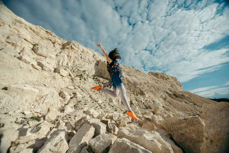Young woman posing and dancing near the beautiful mountains dressed colorful clothesの写真素材