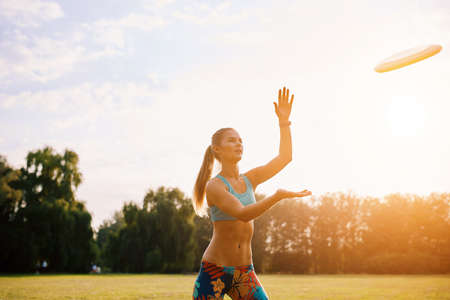 Young athletic girl playing with flying disc in the park. Professional player. Sport conceptの写真素材