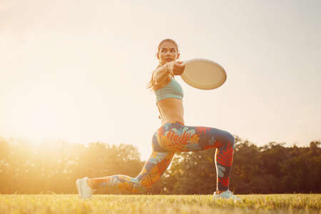 Young athletic girl playing with flying disc in the park. Professional player. Sport concept