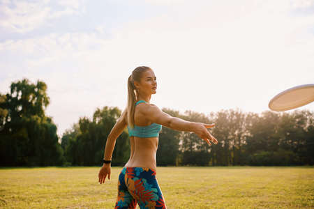 Young athletic girl playing with flying disc in the park. Professional player. Sport conceptの写真素材