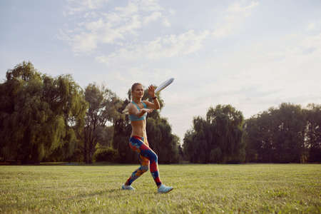Young athletic girl playing with flying disc in the park. Professional player. Sport concept....