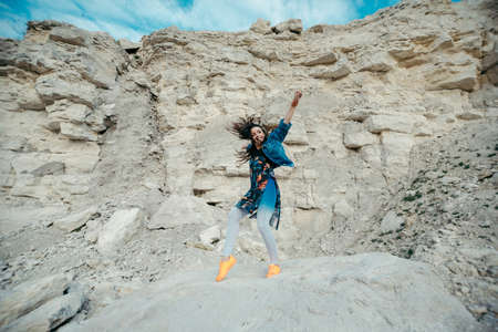 Young woman posing and dancing near the beautiful mountains dressed colorful clothesの写真素材