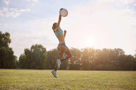 Young athletic girl playing with flying disc in the park. Professional player. Sport conceptの写真素材