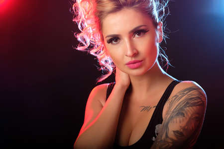 Portrait of sexy tattooed woman posing in the light flashes in studioの写真素材