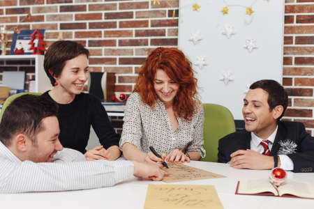 Excited team is writing a letter to Santa while smiling, talking and making wishes for future year. ...