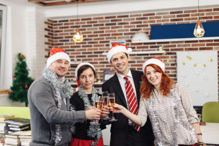 Merry Christmas and Happy New Year 2018. Team is celebrating holiday in modern office. Group of young business people are drinking champagne in coworking.の写真素材