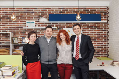 Portrait Of Office Staff Standing In Office. Team is looking at camera and smiling while standing in thei working space.の写真素材