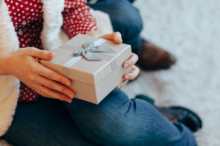 Woman gentle hands holding a present box on the bent legsの写真素材
