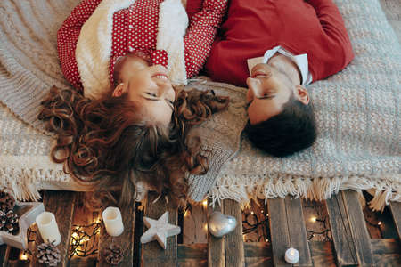 Young couple laying on the bed smiling with heads upside down. Young attractive couple lays on the...
