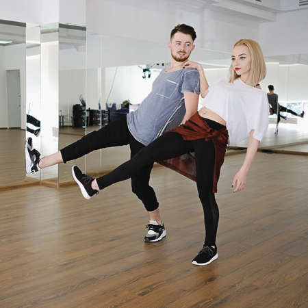 Two young beautiful dancers, man and woman, performing difficult movements in studio, while smiling and enjoying the process. Man and woman in passionate dancing poseの写真素材