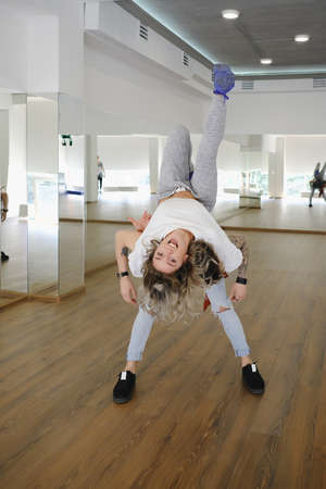 Two young beautiful dancers, man and woman, performing difficult movements in studio, while smiling...