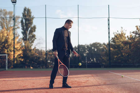 Portrait of confident businessman holding tennis racket in hand looking to jumping ball against...