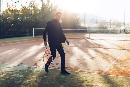 Businessman practicing sport in the mornings to maintain daily tonus, health, to take a break from thoughts. Businessman playing tennis.の写真素材