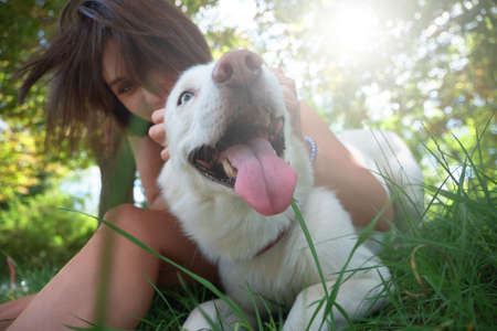 Happy, playful dog with tongue out close up. Woman having a good time playing with her husky pet.