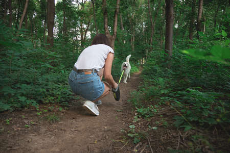 Young modern woman hiking with a dog in the summer landscape. Friendship, people, animals