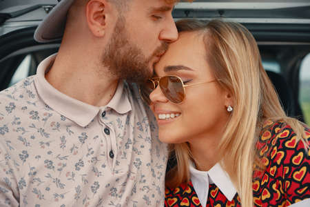 Close up young, attractive man kissing with affection forehead of his beautiful girlfriend and...
