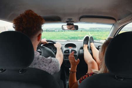Happy couple enjoying on a long drive in a car. Friends driving on road trip on summer day....