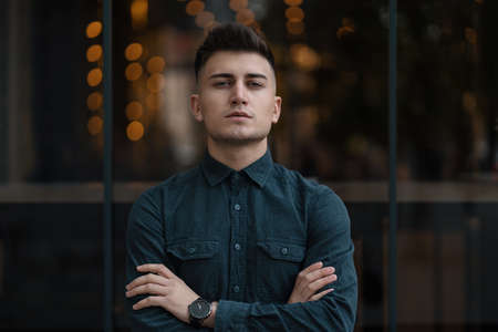 Young man crossed hands close up portrait with lights in the background