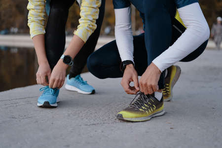 Tying sports shoes. Young couple getting ready for running and fitness training outdoors. Sport, exercise, fitness, workout. Healthy lifestyle.の写真素材