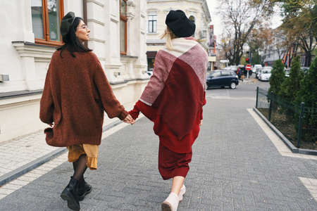 Back view. Carefree fashionable women models in elegant autumn clothes and glasses. Young fashion...