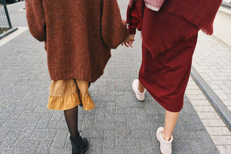 Fall winter fashion outfit details. Back view cropped image of two stylish girls walking on city street. Set of wool clothes, shoes and accessories.の写真素材