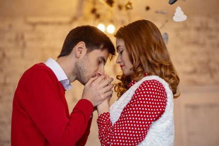Happy loving couple enjoying Christmas. Young man kissing his girlfriend on forehead touching her handsの写真素材