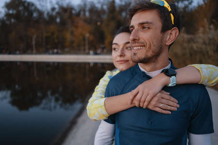Happy sporty couple portrait. Man and woman smiling while hugging. Runners outside resting after running.の写真素材