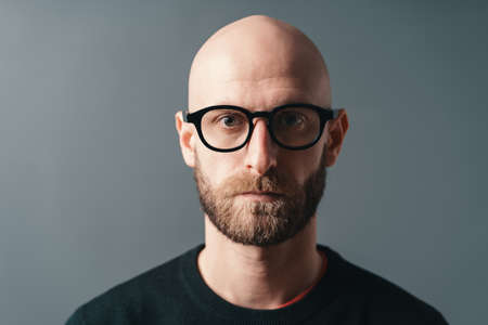 Close-up portrait confident stylish young bearded man wearing glasses with black frame, posing in studio o gray background.の写真素材