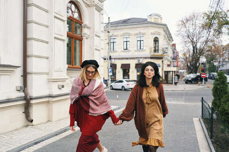 Carefree fashionable women models in elegant autumn clothes and glasses. Young fashion girls in...