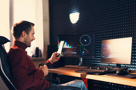 Young man working in the studio using a smartphone in front of the computer.の写真素材