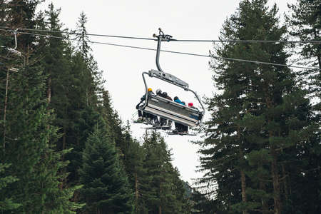 Ski lift lifting people in the Balkans, with fir tree in background