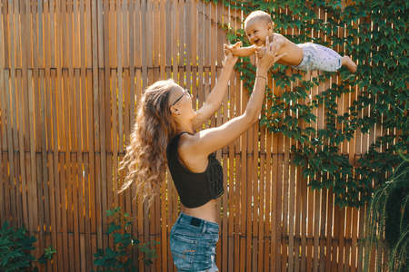 Young mother doing baby yoga for her son in the backyard garden