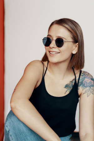 Young girl sitting on a white chair near the red wall. Natural light from the windowの写真素材