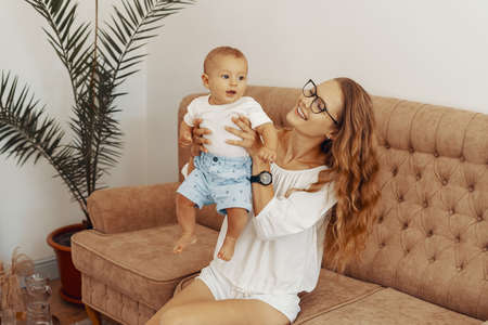 Happy family, mother and baby having fun together at home on the couchの写真素材