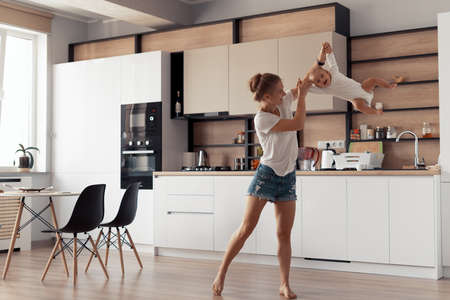 Young mother with baby have fun in the kitchen at homeの写真素材