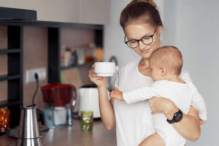 Young mother with baby have fun in the kitchen at homeの写真素材