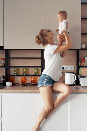Young mother with baby have fun in the kitchen at homeの写真素材