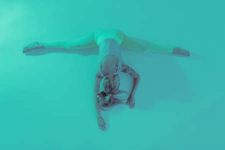 Athletic young woman doing yoga exercise. Dressed in retro sportswear. Neon lights. Specific studio lightの写真素材