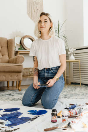Beautiful young woman artist drawing in a comfy home interiorの写真素材