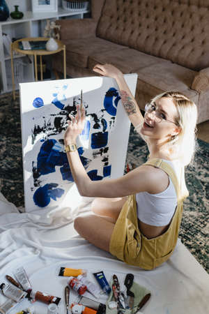 Beautiful young woman artist drawing in a comfy home interiorの写真素材