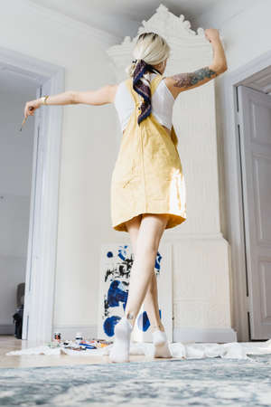 Cheerful dancing girl in a white space with a painting in background in yellow sunny clothes and white socksの写真素材