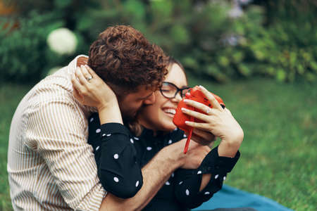 Young couple in love taking a selfie with an instant camera. Lying on the grass in the yard of his...