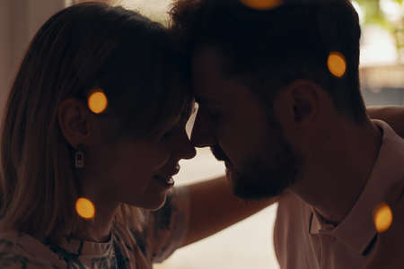 Silhouette of a loving couple hugging. Bokeh effect of garlands. Close up portraitの写真素材