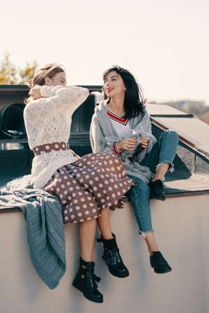 Two attractive girls relaxing on a rooftop in the city. Positive facial expressions, emotions, feelings, body language.の写真素材
